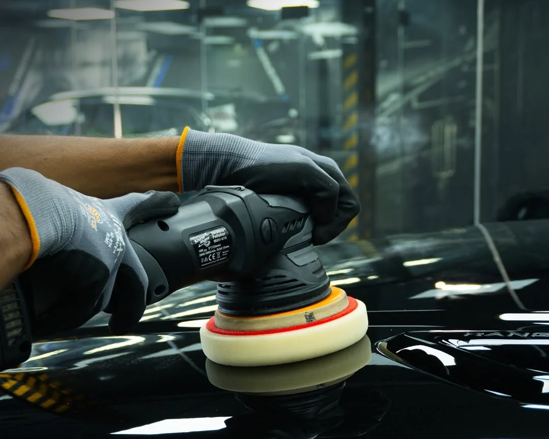 RestorFX technician running a machine polisher across a black Range Rover bonnet