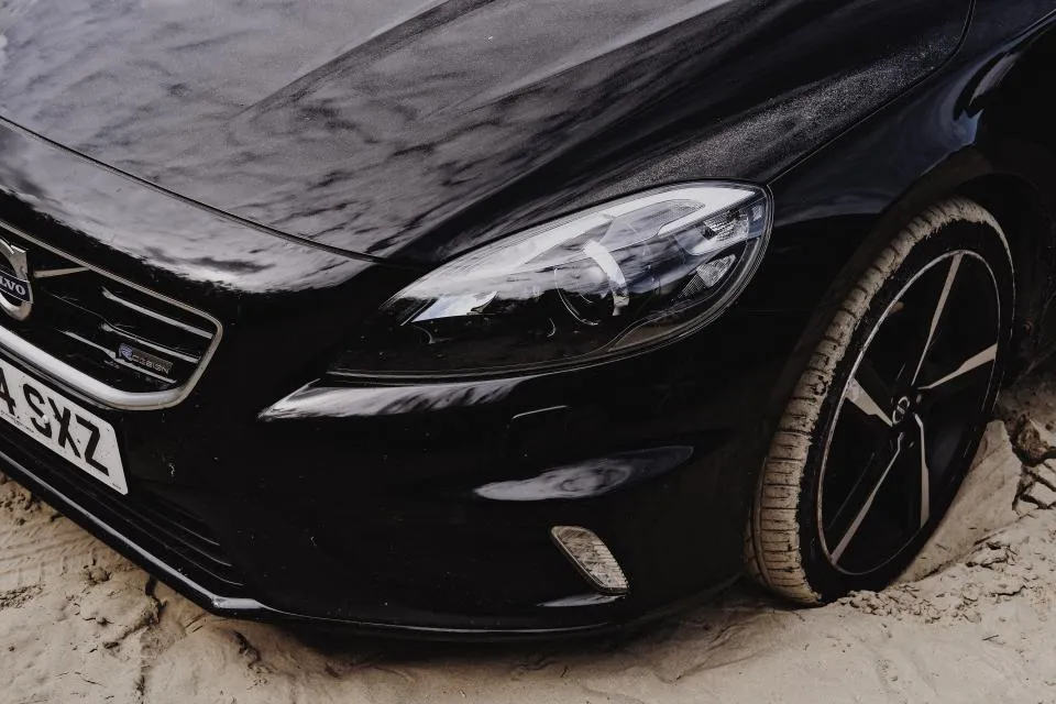 Black car bonnet and headlight with a deep, unmarked gloss finish