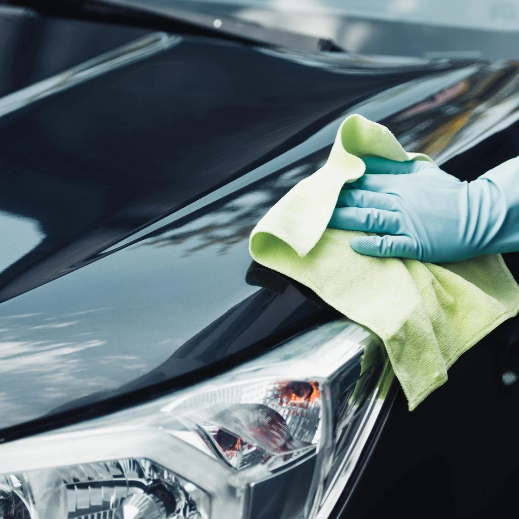 Automotive specialist inspecting and finishing the paint on the front bonnet edge and headlight
