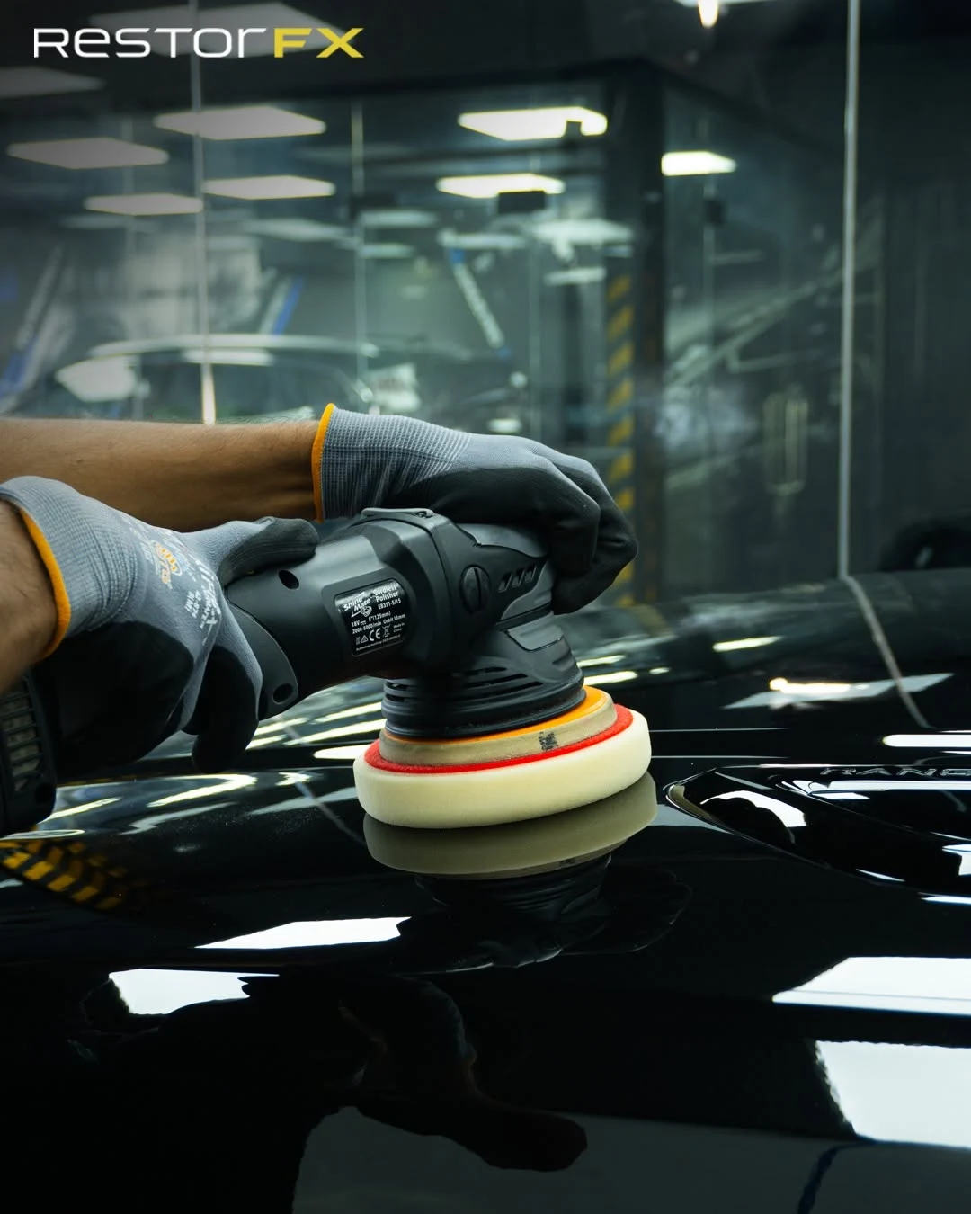 Technician machine polishing clearcoat on a black Range Rover bonnet at RestorFX workshop