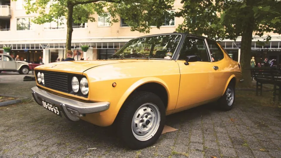 A yellow classic coupe with clean, unbroken paint on the bonnet and wing